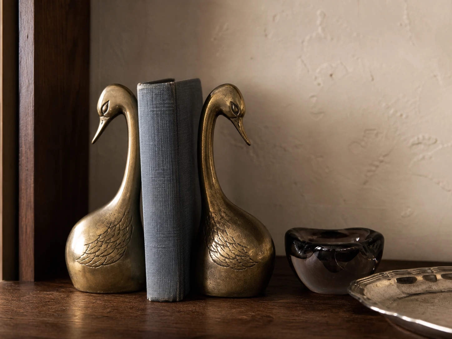 Cygnes en laiton patiné, livre ancien et verre fumé